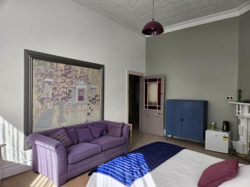 sala de estar con sofá púrpura y cama en Quirky Villa, en Whanganui