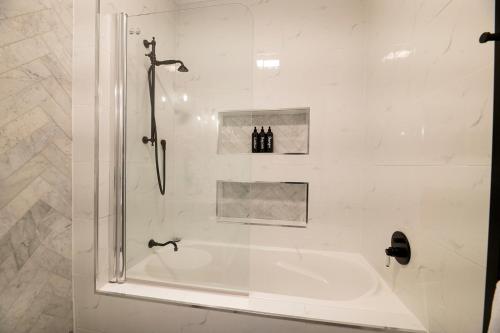 a white bathroom with a shower and a tub at The Grand on Macquarie in Dubbo