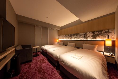 a hotel room with two beds and a flat screen tv at Hotel Forza Kyoto Shijo Kawaramachi in Kyoto
