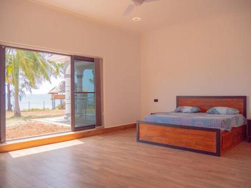 um quarto com uma cama e uma grande janela em Mwambani Beach Villas em Tanga