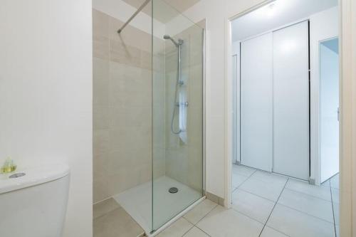 La salle de bains est pourvue d'une douche avec une porte en verre. dans l'établissement Le Havre de Sérénité - Orly - Gare - Place privée, à Athis-Mons