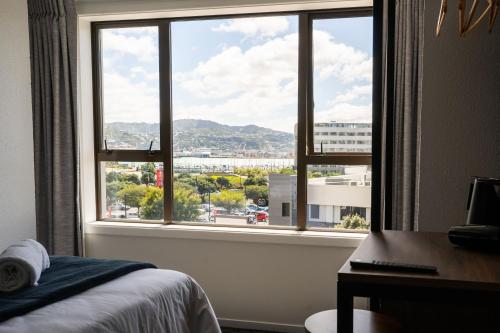 a bedroom with a view of a city from a window at Haka House Wellington in Wellington