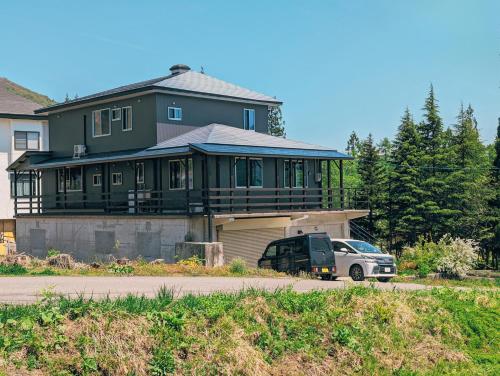 a large house with a car parked in front of it at Crows Nest Norikura by JAMSZ ROYALE in Otari