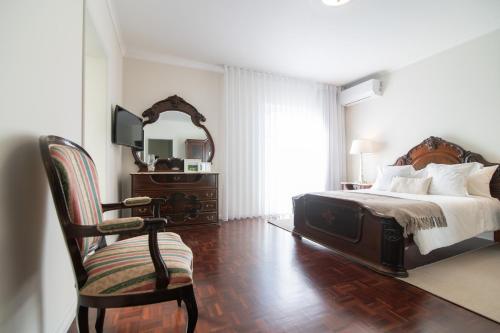 ein Schlafzimmer mit einem Bett, einem Stuhl und einem Spiegel in der Unterkunft Casa Cecilia Meireles in Ponta Delgada