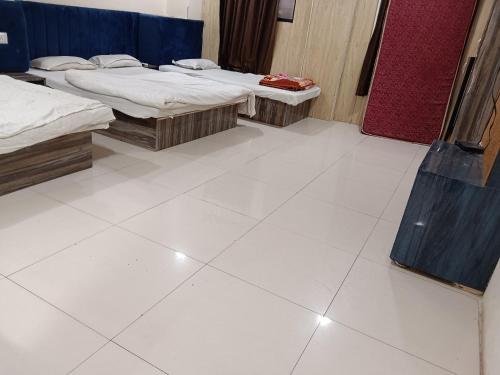Zimmer mit 2 Betten und weißem Fliesenboden in der Unterkunft Hotel Standard in Ujjain