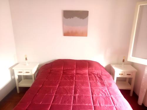 um quarto com uma cama vermelha e duas mesas de cabeceira em HOSPEDAJE DEL PARQUE- Zona centro de Monte Grande-15 min del Aeropuerto de EZE!! ESTACIONAMIENTO GRATIS! em Monte Grande