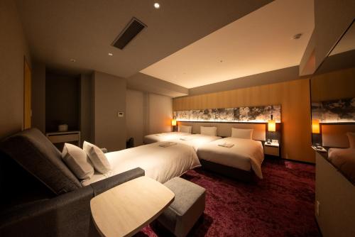 a hotel room with two beds and a couch at Hotel Forza Kyoto Shijo Kawaramachi in Kyoto