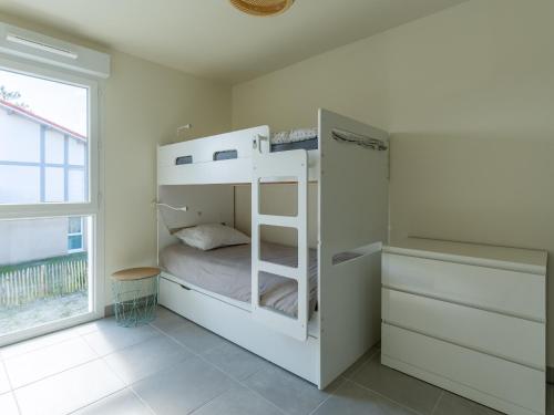 Ce lit superposé blanc se trouve dans un dortoir doté d'une fenêtre. dans l'établissement Appartement Neuf 3* à 2 Pas de l'Océan à Mimizan, 5 Pers, Balcon, Parking - FR-1-50-132, à Mimizan
