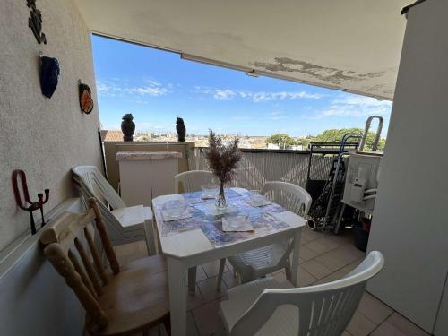 une table blanche et des chaises sur un balcon dans l'établissement Appt Climatisé 4 Pers avec Piscine et Parking, Plage à 200m - FR-1-250-269, au Grau-du-Roi