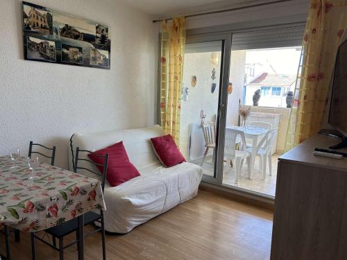un salon avec un canapé blanc et une table ainsi qu'une salle à manger dans l'établissement Appt Climatisé 4 Pers avec Piscine et Parking, Plage à 200m - FR-1-250-269, au Grau-du-Roi