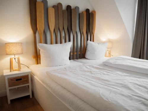 una camera con due letti con lenzuola bianche e due lampade di App Ostseebrise a Timmendorfer Strand