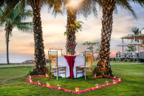 uma mesa e cadeiras entre duas palmeiras em Lovina Beach Club & Resort em Lovina