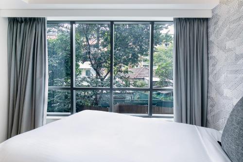 a bedroom with a white bed and a large window at Kith Hotel Darling Harbour in Sydney