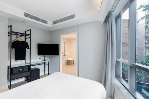 Schlafzimmer mit einem Bett, einem TV und einem Fenster in der Unterkunft Kith Hotel Darling Harbour in Sydney