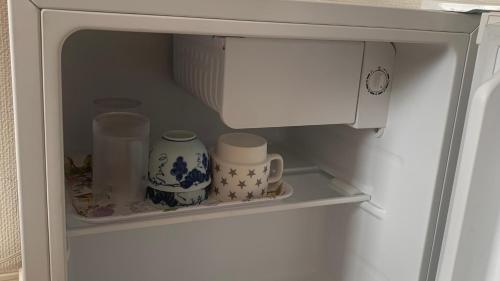 um frigorífico com duas canecas e chávenas numa prateleira em CASA HORIZONTE em Hachioji