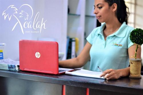 una mujer sentada en una mesa con un portátil rojo en Hotel Xcalak, en Chetumal