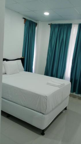 białe łóżko w pokoju z niebieskimi zasłonami w obiekcie Hotel Mendoza Inn w mieście Comayagua
