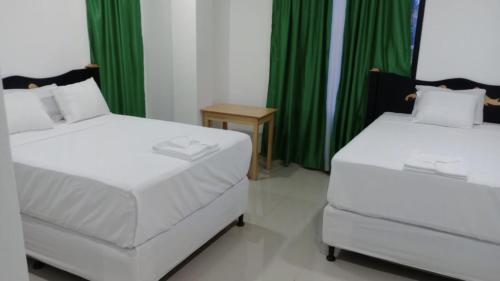 2 łóżka w pokoju z zielonymi zasłonami w obiekcie Hotel Mendoza Inn w mieście Comayagua