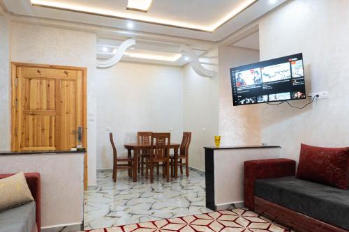 a living room with a tv and a table and chairs at Appartement familial in Dakhla