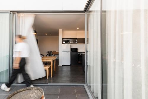 a person walking through a glass door of a kitchen at Change Overnight in Launceston