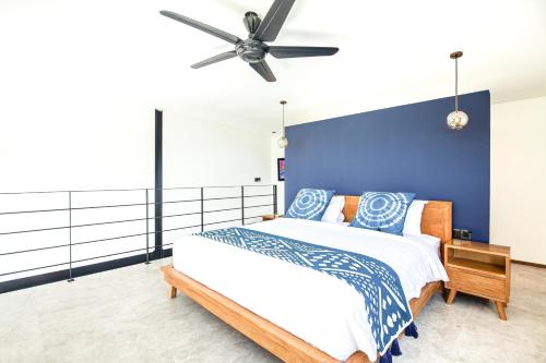 a bedroom with a large bed with a blue wall at Modern Spacious Loft 200m From The Beach Canggu in Canggu