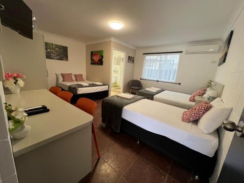 a hotel room with two beds and a desk at Spanish Lace Motor Inn in Townsville