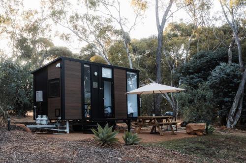 a tiny house with a picnic table and an umbrella at Djindarup Retreat 3 in Prevelly