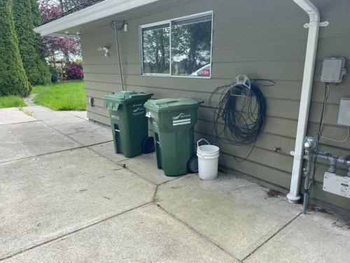 dos cubos de basura verdes sentados fuera de una casa en Cozy Retreat in Richmond en Richmond