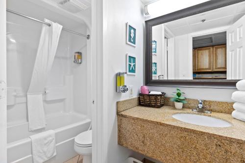 a bathroom with a sink and a tub and a mirror at Oceanfront Oasis in Myrtle Beach