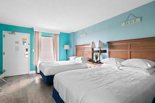 duas camas num quarto de hotel com paredes azuis em Oceanfront Oasis em Myrtle Beach