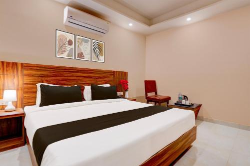 ein Schlafzimmer mit einem großen weißen Bett und einem Stuhl in der Unterkunft Super Townhouse 1363 Hotel Lindo Lugar in Alwar