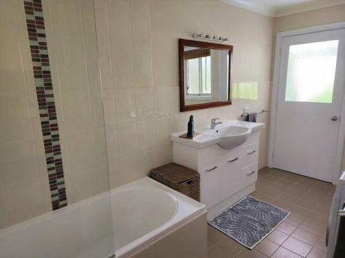 a white bathroom with a tub and a sink at Delaware Retreat in Mount Panorama