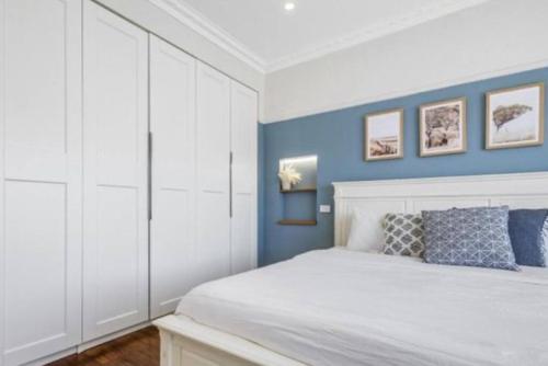 a bedroom with a white bed and blue walls at Lauriston Charmer in Kyneton