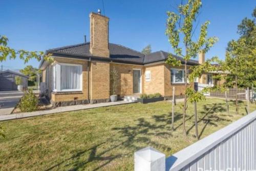 a house with a white fence in front of a yard at Lauriston Charmer in Kyneton