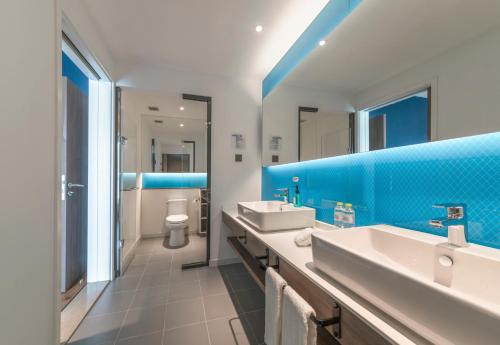 a bathroom with two sinks and a blue wall at Holiday Inn Express Qingdao Chengyang Central by IHG in Qingdao