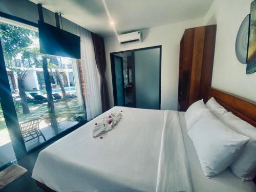 Schlafzimmer mit einem Bett mit weißer Bettwäsche und einem Fenster in der Unterkunft Tuong Vy Boutique Hotel Mui Ne in Mui Ne