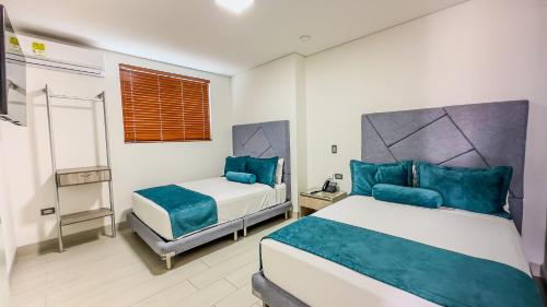 a bedroom with two beds with blue pillows at Hotel Marco Polo Rodadero in Santa Marta