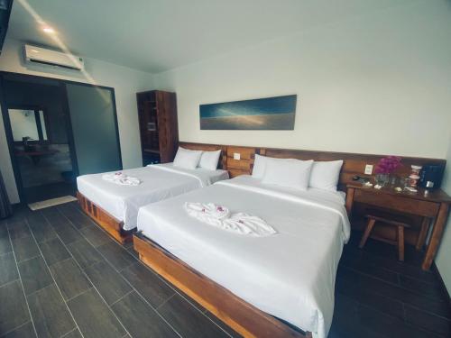 two beds in a hotel room with white sheets at Tuong Vy Boutique Hotel Mui Ne in Mui Ne