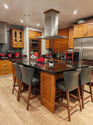 a kitchen with a island with chairs and a refrigerator at Mediterranean Villa in Heredia