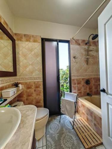a bathroom with a toilet and a tub and a sink at Mediterranean Villa in Heredia