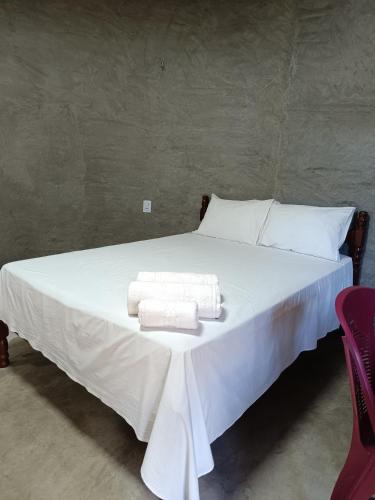 a bed with white sheets and towels on it at Chalé Rj Rio in Santo Amaro