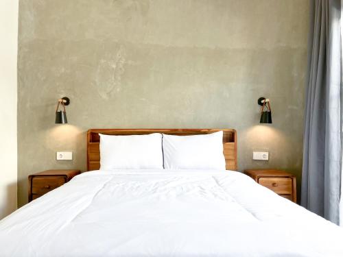 a bedroom with a white bed with two lamps on the wall at Adi surya guest house in Seminyak