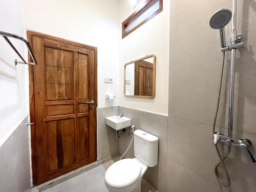 a bathroom with a toilet and a wooden door at Adi surya guest house in Seminyak