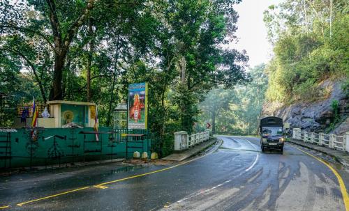 a bus is driving down a road with trees at Rock View Sinharaja in Kalawana