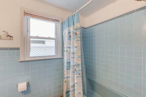 ein blau gefliestes Bad mit einer Dusche und einem Fenster in der Unterkunft Pet-Friendly Long Beach Island Home Walk to Beach in Long Beach