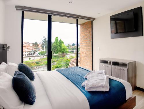 a bedroom with a large bed with a large window at Hotel & Suites en Cuenca, Venue Batán in Cuenca