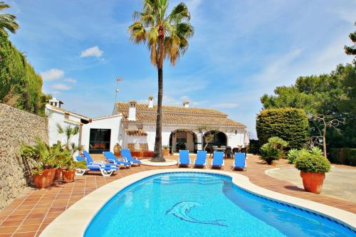 a villa with a swimming pool and palm trees at Finca Coello - charming, Spanish finca style holiday villa in Benissa in Benissa