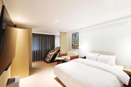 um quarto de hotel com uma cama e uma cadeira em Browndot Incheon Airport New City em Incheon