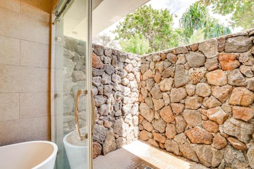 a bathroom with a glass shower and a stone wall at Luxe Oceanfront Waianae Home with Lanai - Near Beach in Waianae