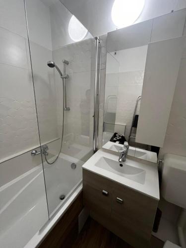 a white bathroom with a shower and a sink at Small Studió Apartman in Pécs